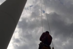 Pomiar rezystancji uziemienia - pracownik windujący się do końcowej części łopaty wirnika elektrowni wiatrowej